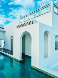 ein weißes Haus mit Swimmingpool und blauem Himmel in der Unterkunft Renjana Beach House in Bira