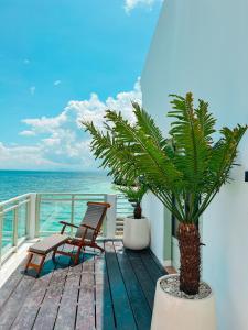 a balcony with two chairs and a palm tree at Renjana Beach House in Bira