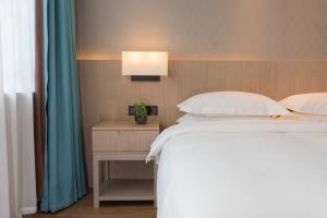 Un pat sau paturi într-o cameră la 义乌曼卡兰酒店国际商贸城店Yiwu kaiding Hotel