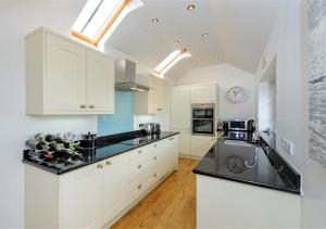 a kitchen with white cabinets and black counter tops at Jennys Cottage in Abersoch