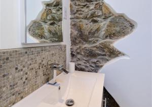 a bathroom with a sink and a rock wall at Jennys Cottage in Abersoch