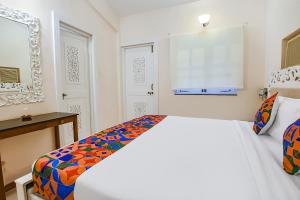 um quarto branco com uma cama com um cobertor colorido em FabHotel Prime Pool Point Highland, Candolim Beach em Candolim