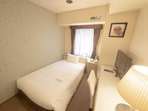 a small room with a white bed and a window at Shin-Yokohama Kokusai Hotel in Yokohama