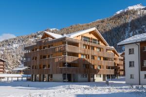 un bâtiment dans la neige avec une montagne en arrière-plan dans l'établissement Montela Apartments by fewo-plan SAAS210, à Saas-Grund