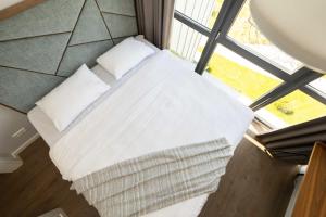 a bed with white sheets and pillows next to a window at THE BEST OF ŠVENTOSIOS VARTAI, By Cohost in Šventoji