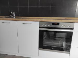 una cocina con armarios blancos y horno negro en Appartement Illertal, nähe A7 , Legoland, 2 Schlafzimmer en Vöhringen