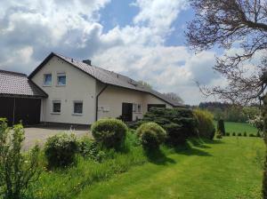 une maison blanche avec une cour verdoyante entourée de buissons dans l'établissement Appartement Illertal, nähe A7 , Legoland, 2 Schlafzimmer, à Vöhringen