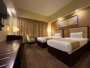 a hotel room with two beds and a desk at Hotel O2 Oxygen in Kolkata