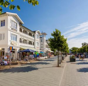 a street with a white building and tables and chairs at Villa Hildegard Appartement 2 in Binz