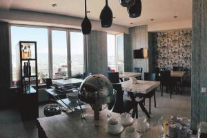a dining room with tables and chairs and windows at Panorama 360° Hotel in Tbilisi City