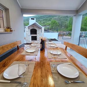 einen langen Holztisch mit Tellern und Weingläsern in der Unterkunft Villa Ana Marija - Family destination with heated pool in Lećevica