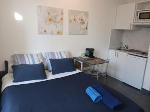 1 dormitorio con 1 cama con almohadas azules y cocina en studio à 2 mn à pied de la plage en Niza