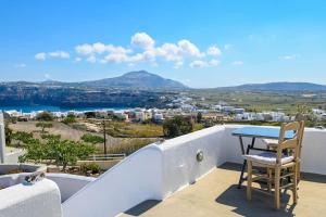 stół i krzesło na balkonie domu z widokiem w obiekcie Villa Solasta #2 with jacuzzi in Santorini w Akrotiri
