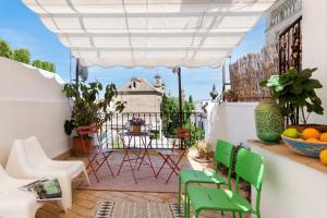 eine Terrasse mit grünen Stühlen und einem Tisch auf dem Balkon in der Unterkunft San Luis Luxury House with Terrace in Sevilla