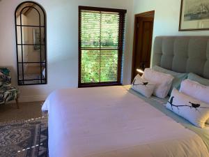 um quarto com uma grande cama branca e uma janela em The Guardian Hermanus Luxury Self-Catering Hemel en Aarde Valley em Hermanus