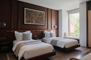 una habitación de hotel con 2 camas y un cuadro en la pared en Munno Villa, en Canggu
