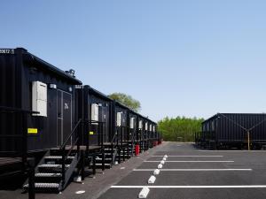 Une rangée de voitures de train noires garées dans un parking dans l'établissement HOTEL R9 The Yard Tsu, à Tsu