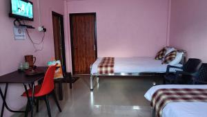 Cette chambre comprend deux lits, une table et une télévision. dans l'établissement StayHome Away from Home, à Cherrapunji