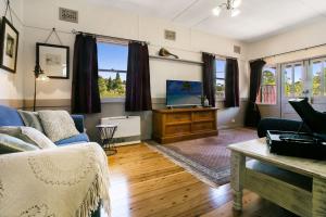 ein Wohnzimmer mit einem Sofa und einem TV in der Unterkunft Carinya Cottage in Katoomba
