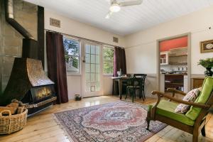 un salon avec une cheminée et un fauteuil vert dans l'établissement Carinya Cottage, à Katoomba