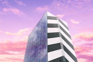 ein hohes Glasgebäude mit einem wolkigen Himmel im Hintergrund in der Unterkunft Zonar Zagreb by Maistra City Vibes in Zagreb