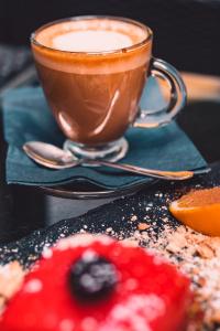 una tazza di caffè seduta su un tavolo accanto a un dolce di Business Hotel Plovdiv a Plovdiv
