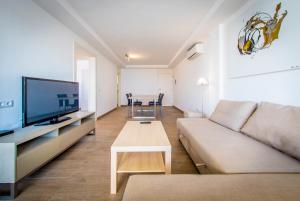 ein Wohnzimmer mit einem Sofa, einem TV und einem Tisch in der Unterkunft 06 LUXURY MARINA 3 BEDROOMS in Ibiza-Stadt