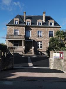 a large brick house with a black roof at La Granitiere Maison de Charme in Saint-Vaast-la-Hougue