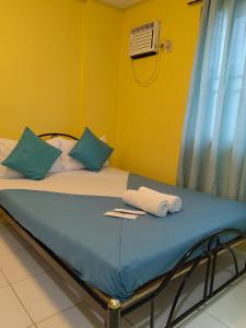 a bed with blue pillows and towels on it at YellowPad Hotel (SM-Eco) in Davao City