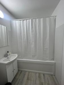 a white bathroom with a shower curtain and a sink at Garsoniera 2 Mega Mall in Bucharest