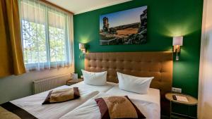 ein Schlafzimmer mit einem großen Bett und einer grünen Wand in der Unterkunft Acron-Hotel Quedlinburg in Quedlinburg