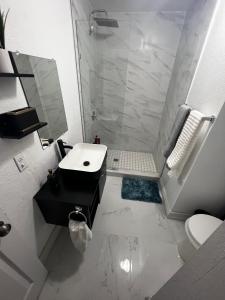 uma casa de banho branca com um chuveiro e um lavatório. em Miami Gardens Comfort Suite by Hard Rock Stadium em Miami Gardens
