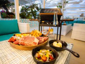 宮古島にあるGLAMTECH RESORTS HEAVENのグリルの横に2杯の食べ物を盛り付けたテーブル