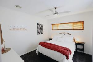 a bedroom with a white bed with a red blanket at Two Rivers - Harriet in Kingscote