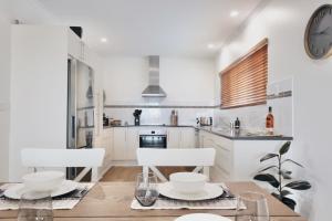 a kitchen with a table and chairs and a clock at Two Rivers - Harriet in Kingscote
