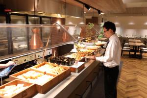 Ein Mann steht in einer Küche und bereitet Essen vor. in der Unterkunft Osaka Corona Hotel in Osaka