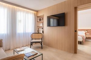 ARTIEM Apartamentos في ماهون: غرفة معيشة مع أريكة وتلفزيون على الحائط