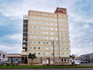 a tall building with a sign on top of it at Hotel Route-Inn Sapporo Shiroishi in Sapporo