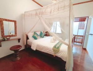 a bedroom with a canopy bed and a window at Apilapa Hotel in Chiang Mai