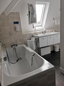 La salle de bains blanche est pourvue d'une baignoire et d'un lavabo. dans l'établissement Hotel La Granitiere, à Saint-Vaast-la-Hougue