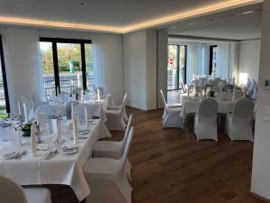 Cette chambre dispose de tables blanches, de chaises blanches et de fenêtres. dans l'établissement Voss Villa, à Leipzig