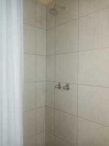 uma casa de banho com chuveiro e azulejos brancos em Lisokhanya GuestHouse em East London