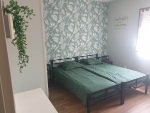 a bedroom with a bed with green sheets and a wallpaper at LE REFUGE in Lurcy-Lévis