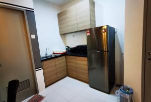 a kitchen with a stainless steel refrigerator and wooden cabinets at Chillax @ TT3 Soho in Kuching