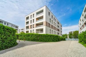 a large white building with bushes in front of it at Kolska Grey Apartment in Warsaw