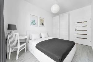 a bedroom with a bed and a desk and a chair at Kolska Grey Apartment in Warsaw