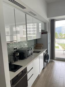 a kitchen with white cabinets and a sink and a microwave at Brand new Studio on Yas Island, Abu Dhabi in Abu Dhabi