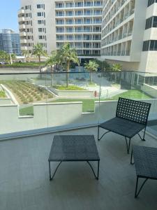 two chairs and tables on a balcony with buildings at Brand new Studio on Yas Island, Abu Dhabi in Abu Dhabi