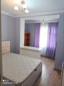 a bedroom with a bed and a window with purple curtains at Nakhchivan Center in Naxçıvan
