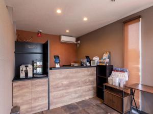 a coffee shop with a counter and a coffee machine at HOTEL R9 The Yard Saito in Saito